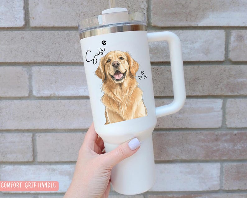 May include: White insulated tumbler with a handle, featuring a golden retriever illustration, paw print, and hearts. The name "Susi" is written in cursive. The tumbler has a silver rim and a clear lid.