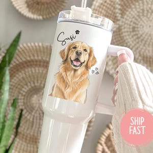 May include: White insulated tumbler featuring a golden retriever illustration with the name "Susi" and paw print. The tumbler has a handle and a clear lid with a straw. Small hearts are next to the dog's image.