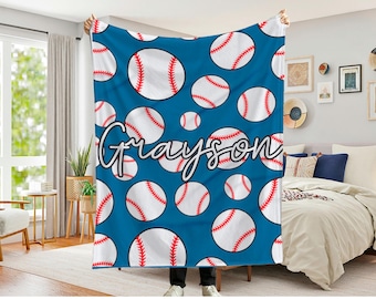 May include: A blue baseball-themed blanket with a repeating pattern of white baseballs with red stitching. The name "Grayson" is written in a cursive font across the blanket. The blanket is held up in front of a bedroom.