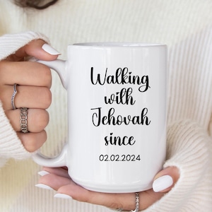 May include: White ceramic mug with the text "Walking with Jehovah since 02.02.2024" in black script. The mug has a large handle and is held by a person wearing a white sweater.