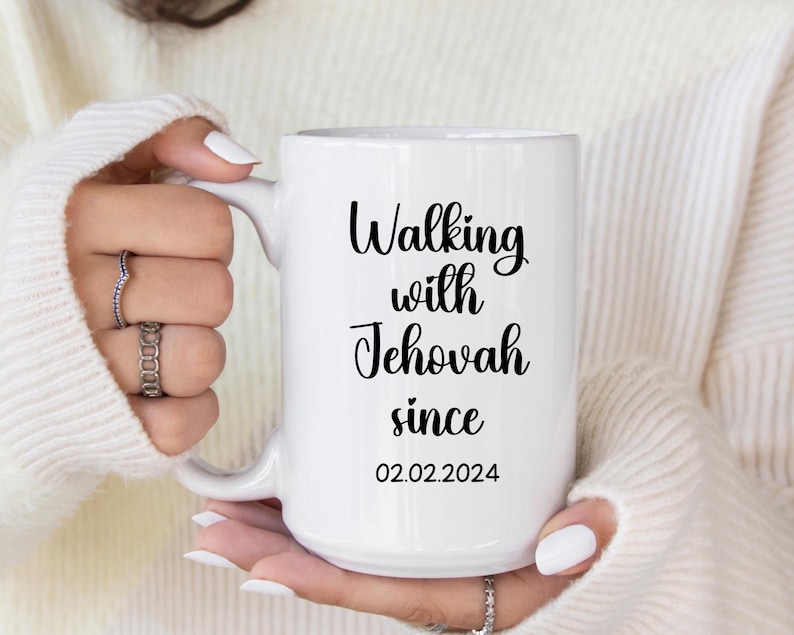 May include: White ceramic mug with the text "Walking with Jehovah since 02.02.2024" in black script. The mug has a large handle and is held by a person wearing a white sweater.
