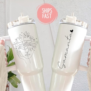May include: White insulated tumbler with a handle and a clear lid. One tumbler features a black line drawing of a face and furniture. The other tumbler has the name "Samantha" in black script with a heart.