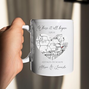 May include: White ceramic mug with a black and white map of a city in the shape of a heart. The text "Where it all began" is written above the map. The coordinates "39.17061N 76.36581W" and the names "Allison & Leonardo" are written below the map.