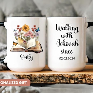 May include: White ceramic mug with a black handle and rim. One side features an open book with colorful flowers and butterflies, the name "Emily" is below. The other side reads "Walking with Jehovah since 02.02.2024".