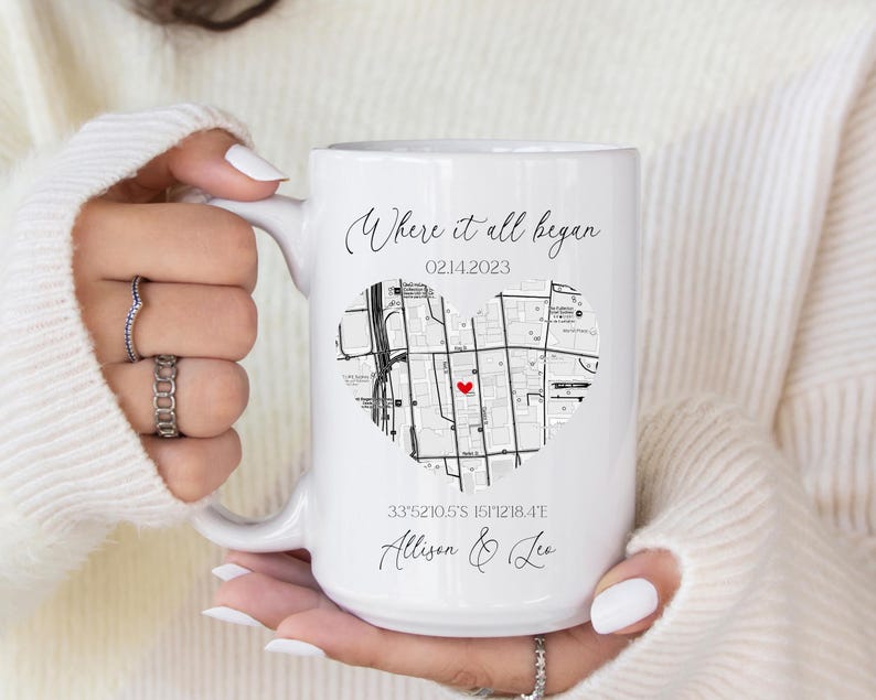 May include: White ceramic mug with a black and white map of a city in the shape of a heart. The text "Where it all began" is at the top of the mug, with the date "02142023" below it. The coordinates "33&deg;52'10.5"S 151&deg;12'18.4"E" are printed below the map, along with the names "Allison & Lee".