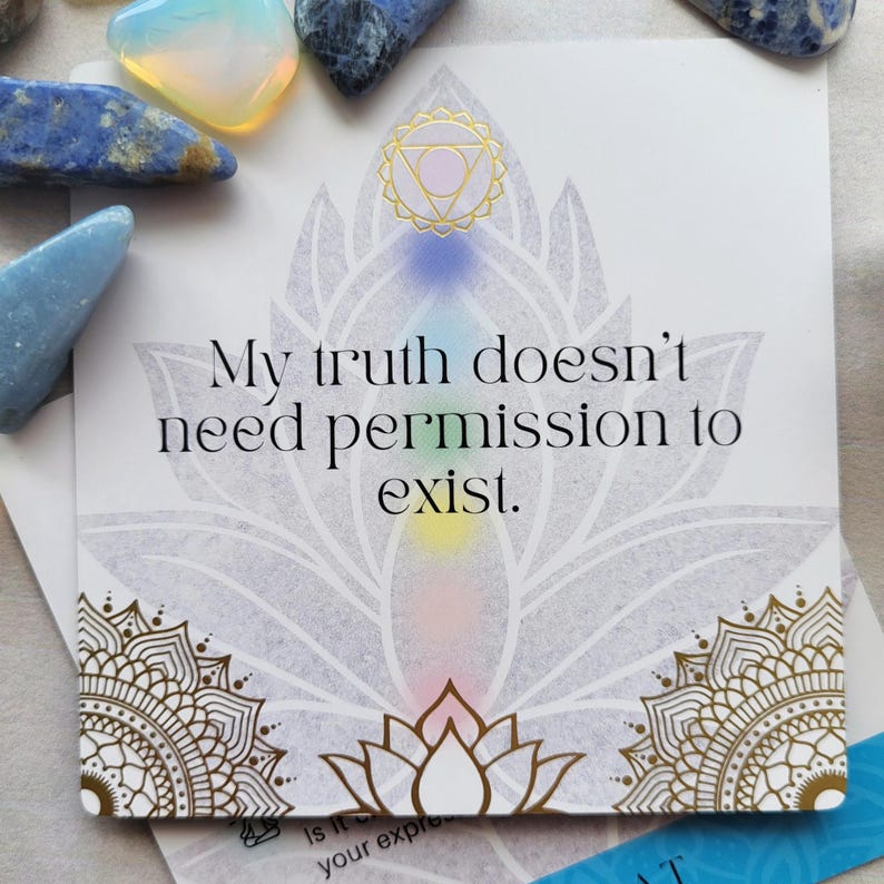 May include: A white card with the text "My truth doesn't need permission to exist." features a lotus flower design with gold accents and a rainbow gradient. Various blue and clear crystals are scattered around the card.