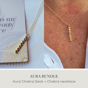 May include: A gold-colored necklace with a vertical row of seven colorful gemstones. The necklace is displayed with a card that has the text "is my beauty re" and a decorative mandala design. The image also shows the text "AURA BUNDLE" and "Aura Chakra Deck + Chakra necklace".