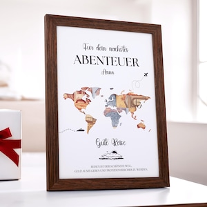 Könnte beinhalten: Ein gerahmter Druck mit einem Weltkarten-Design aus farbenfrohen Banknoten. Der Druck hat einen dunkelbraunen Holzrahmen und enthält den Text "Fur dein nachstes ABENTEUER Anna" und "Gute Reise". Eine Geschenkbox mit rotem Band ist sichtbar.