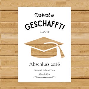 May include: A white graduation announcement with the text "Du hast es GESCHAFFT!" and "Abschluss 2026". It features a wooden graduation cap illustration and the names "Leon", "Oma & Opa".