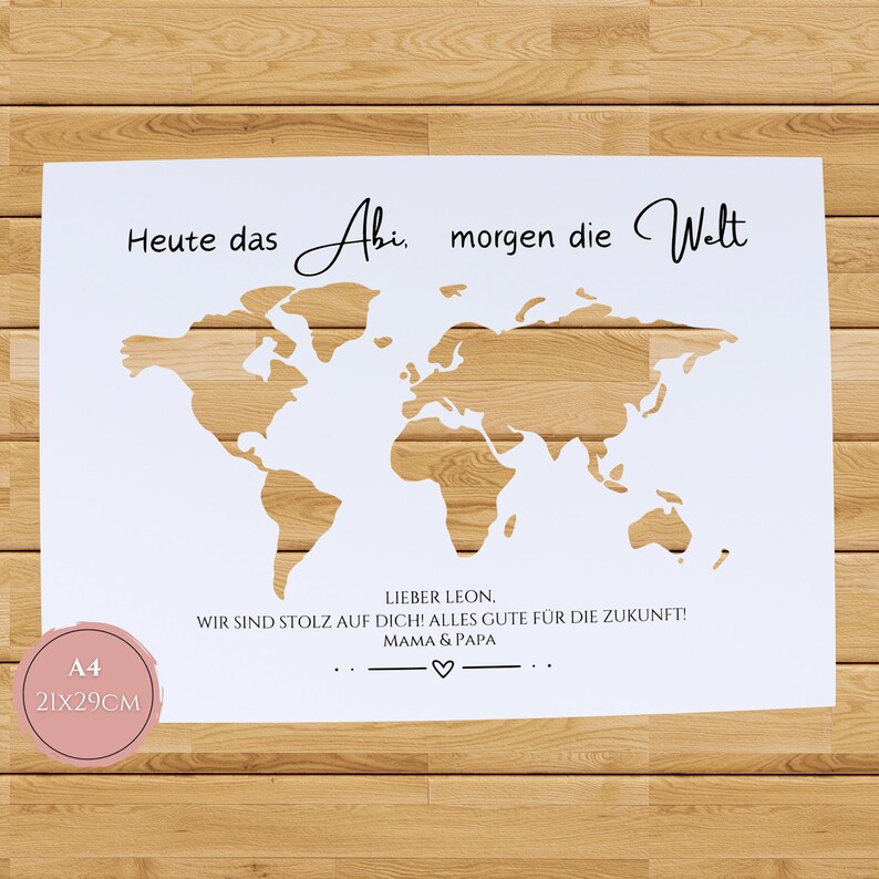 Pu&ograve; includere: Una stampa rettangolare bianca con un ritaglio di mappa del mondo che rivela un motivo a venature del legno. Il testo recita: Heute das Abi, morgen die Welt. Sotto: LIEBER LEON, WIR SIND STOLZ AUF DICH! ALLES GUTE F&Uuml;R DIE ZUKUNFT! MAMA & PAPA. &Egrave; visibile un'etichetta rosa A4 21x29cm.