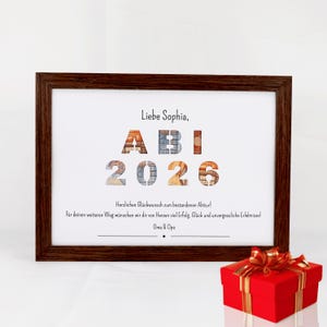Pu&ograve; includere: Una cornice in legno marrone scuro contenente una stampa bianca con il testo "Liebe Sophia, ABI 2026" dove le lettere e i numeri sono riempiti con immagini di banconote. Sotto c'&egrave; un testo in tedesco di congratulazioni, firmato "Oma & Opa".