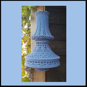 May include: A blue crocheted lampshade with a two-tiered design. The lampshade is hanging from a black chain.