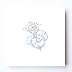 May include: A square white card featuring a centered light blue monogram of the letters S and B intertwined in an ornate, calligraphic script style with decorative flourishes and curved lines forming a symmetrical, elegant graphic design.