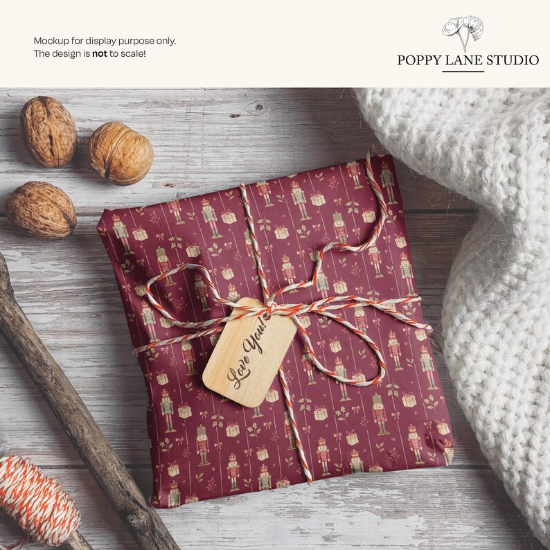May include: A wrapped gift with a burgundy background and a pattern of nutcrackers and gifts. The gift is tied with twine and a tag that says "Love You!". Walnuts and a white knitted blanket are also in the image.