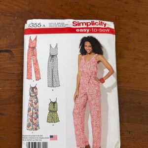 May include: A Simplicity easy-to-sew pattern envelope featuring a woman in a red and white patterned jumpsuit. The envelope displays several jumpsuit designs, including floral and solid color options. The size range is XXS-XXL.