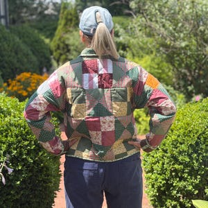 May include: A long-sleeved quilted jacket featuring a patchwork design composed of various fabric squares in shades of green, red, yellow, and white. The jacket has a collared neckline, a button-up front, and a multi-colored geometric pattern.
