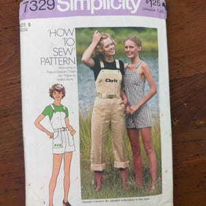 May include: A Simplicity 7329 sewing pattern envelope for size 8 misses. The front features illustrations and photographs of overalls and shortalls with the text 'HOW TO SEW PATTERN', 'Including a Tissue Lesson Chart on How to make darts', and 'Includes transfers for alphabet embroidery in two sizes'.