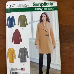 May include: Simplicity sewing pattern 1067, featuring a woman wearing a tan coat. The pattern includes illustrations of various coat designs in blue, green, burgundy, yellow, and gray. The text "easy-to-sew" is displayed prominently.