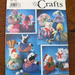 May include: Simplicity Crafts pattern 7043 featuring various stuffed animal designs, including a mouse, bunny, bear, duck, cow, and chicken. The pattern includes instructions for creating fabric crafts with decorative elements.