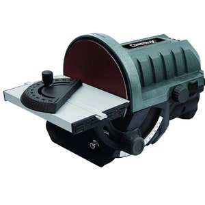 May include: A grey and black electric sander with a sanding disc and a tilting table. The sander has a black power cord and a knob for adjusting the angle of the table.
