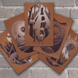 May include: Set of five illustrated cards featuring various creatures, including a wolf, a snake, a ram, a bird, and a figure in a hooded cloak. The cards are printed on brown paper with a textured surface.