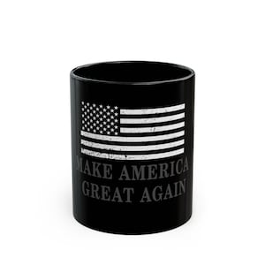 May include: Black ceramic mug featuring a distressed American flag design. The mug has the phrase "MAKE AMERICA GREAT AGAIN" printed below the flag. A patriotic themed mug.