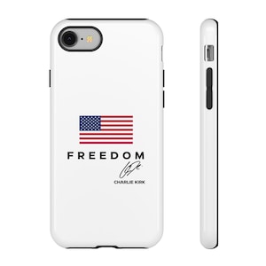 Op de afbeelding: Witte telefoonhoes met de Amerikaanse vlag, het woord "FREEDOM" in zwart, een handtekening en de naam "CHARLIE KIRK". De hoes heeft een zwarte rand en is ontworpen voor een mobiele telefoon.