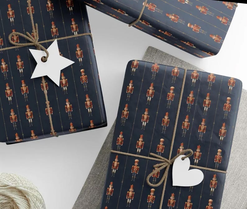 May include: Several wrapped gifts with navy blue paper featuring a repeating pattern of toy soldiers in red and gold. The gifts are tied with twine and have white star and heart-shaped tags.