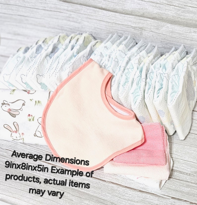 May include: A set of baby essentials including a pink bib, a stack of white and blue patterned baby nappies, and a stack of pink and white face cloths. Average Dimensions 9in x 8in x 5in. Example of products, actual items may vary.