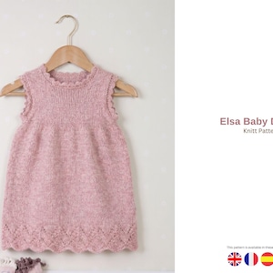 May include: A light pink knitted baby dress with a scalloped hem and neckline, hanging on a wooden hanger. The dress is sleeveless and has a textured knit pattern. The text "Elsa Baby Dress Knitt Pattern" is visible.