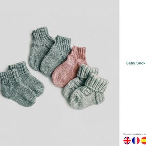 Op de afbeelding: Een verzameling handgebreide babysokken in verschillende kleuren, waaronder grijs en roze. De sokken zijn gerangschikt op een lichte achtergrond. De tekst "Baby Socks Pattern" is zichtbaar in de afbeelding.