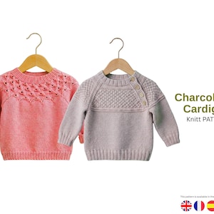 Puede incluir: Dos cárdigans para bebés en perchas de madera. Uno es rosa claro con un patrón de punto decorativo en el pecho. El otro es gris claro con un diseño de punto texturizado y tres botones en el hombro. El texto "Charcol Baby Cardigans" es visible.