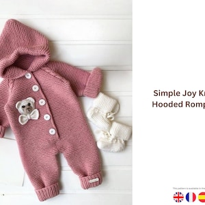 Op de afbeelding: Een stoffig roze gebreide romper met capuchon voor een baby, met een teddybeer applicatie en witte knopen. Inclusief bijpassende witte gebreide slofjes. De tekst "Simple Joy Knit Hooded Romper" is zichtbaar.
