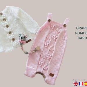Puede incluir: Un cárdigan blanco tejido y un pelele rosa tejido con un diseño de hoja de uva. El cárdigan tiene botones de madera y el pelele tiene botones de madera en las correas. Un chupetero para bebé con un oso está unido al cárdigan. El texto dice "GRAPE LEAF ROMPER AND CARDIGAN."