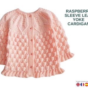 May include: A light pink knitted cardigan with a heart-shaped pattern. The long-sleeved sweater has a round neckline and is buttoned down the front. The text "RASPBERRY SLEEVE LEAF YOKE CARDIGAN" is displayed on the upper right.