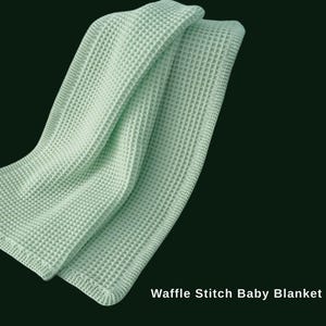 May include: A light green waffle-stitch baby blanket, draped against a dark green background. The blanket features a textured, grid-like pattern. The text "Waffle Stitch Baby Blanket Pattern" is visible.