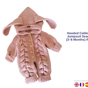 Op de afbeelding: Een stoffig roze baby-overall met een capuchon en kabelbreiwerk. De capuchon heeft lange, slappe oren. De overall heeft houten knopen aan de voorkant. De tekst op de afbeelding luidt "Hooded Cable Baby Jumpsuit Seamless (3-6 Months) Romper."