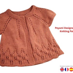 May include: A short-sleeved, coral-colored knitted jacket with a round neckline and decorative openwork details. The jacket features the text "Peyami Designer Jacket Knitting Pattern".