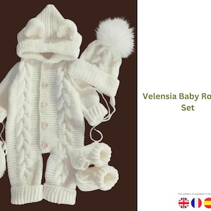 May include: A cream-colored baby romper set. The set includes a hooded romper with a cable knit design, a beanie with bear ears, a beanie with a white pom-pom, mittens, and booties. The text "Velensia Baby Romper Set" is visible.