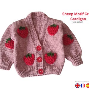 Peut inclure: Un cardigan court rose tricoté avec des appliqués de fraises rouges et des feuilles vertes. Le cardigan a un col en V, trois boutons rouges et le texte "Sheep Motif Crop Cardigan". Les manches sont bouffantes.