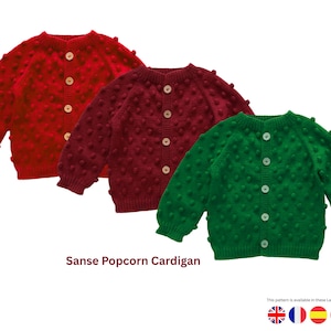 Può includere: Tre cardigan abbottonati in rosso, bordeaux e verde. I maglioni hanno un design a punto popcorn strutturato e maniche lunghe. Il testo "Sanse Popcorn Cardigan" è nella parte inferiore dell'immagine.