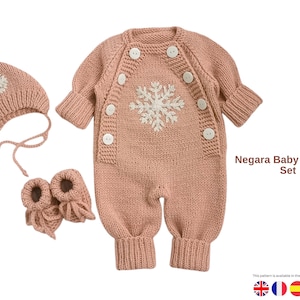 May include: A knitted baby romper set in a soft pink color. The set includes a romper with a snowflake design, a matching hat, and booties. The romper has white buttons and is designed for comfort and warmth.