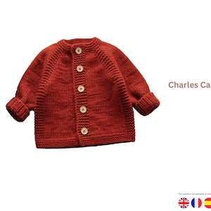 Könnte beinhalten: Ein rostfarbener Strickcardigan mit Rundhalsausschnitt und langen Ärmeln. Der Pullover hat fünf Holzknöpfe auf der Vorderseite und den Text "Charles Cardigan". Ein gemütliches, handgefertigtes Kleidungsstück.