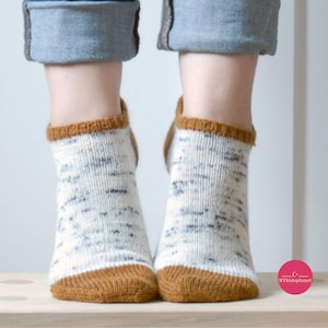 May include: A pair of white ankle socks with a brown trim. The socks have a speckled pattern.