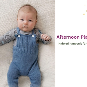 May include: A baby wearing a blue knitted jumpsuit with buttons. The jumpsuit has a ribbed texture and is a light blue colour. The baby is lying on a white blanket.