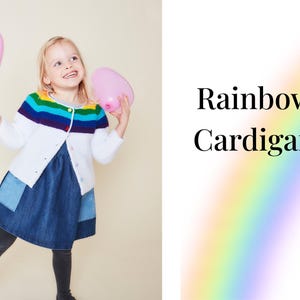 May include: A young girl wearing a white cardigan with a rainbow stripe across the chest. She is holding two pink heart-shaped balloons.