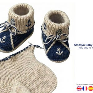 May include: Hand-knitted baby boots in cream and navy blue, featuring an anchor design. The boots have a cream-colored cuff and a navy blue foot with white anchor embroidery. The text "Amasya Baby Boots Very Easy To make" is visible.