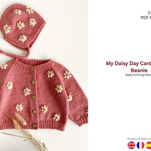 Könnte beinhalten: Ein staubrosa Baby-Cardigan- und Mützen-Set, verziert mit weißen Gänseblümchen-Applikationen. Der Cardigan hat Holzknöpfe und lange Ärmel. Die Mütze hat Bindebänder. Der Text auf dem Bild lautet "My Daisy Day Cardigan and Beanie Baby Knitting Patterns."
