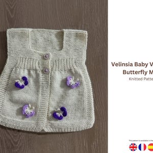 Puede incluir: Un chaleco de bebé tejido de color beige claro con un motivo de mariposa. El chaleco tiene un escote cuadrado, dos pequeños bolsillos y se abrocha con tres botones. Está decorado con aplicaciones de mariposas moradas y blancas. El texto "Velinsia Baby Vest with Butterfly Motif" es visible.