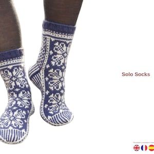 May include: A pair of blue and white knitted socks with a snowflake pattern. The socks have a blue cuff and heel, with a white and blue design. The text "Solo Socks" is visible in the image.